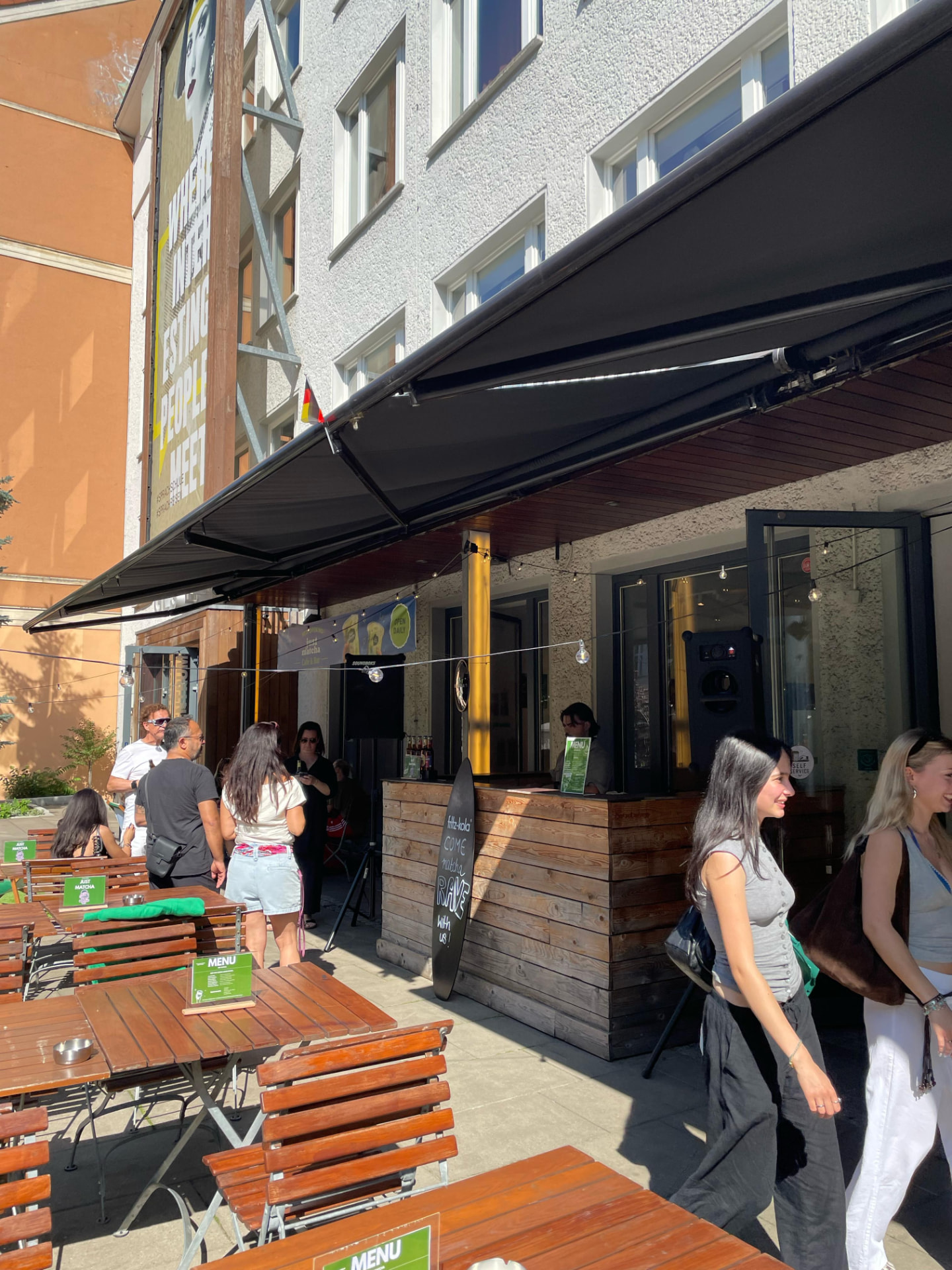 Terrasse mit Gästen vor dem Just Matcha Studio im GLS Campus